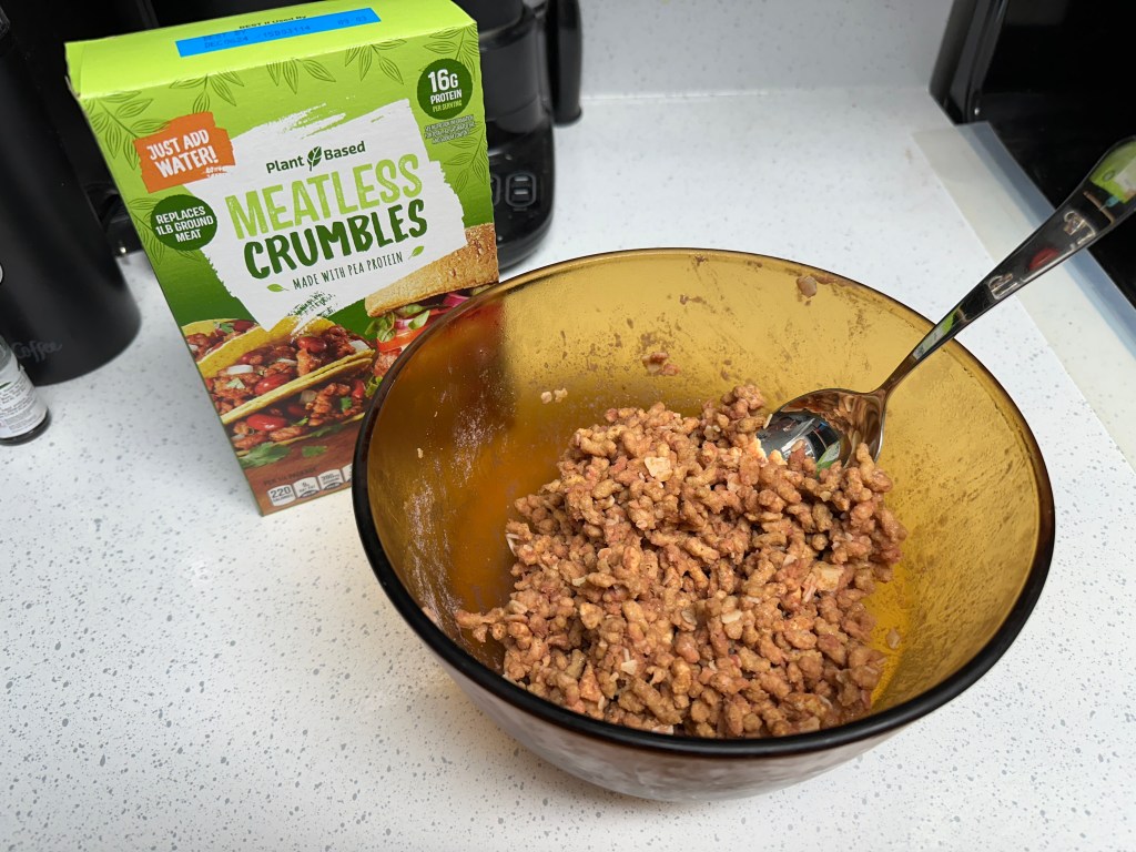 Photo of Aldi's meatless crumbles mixed in a bowl next to the box.